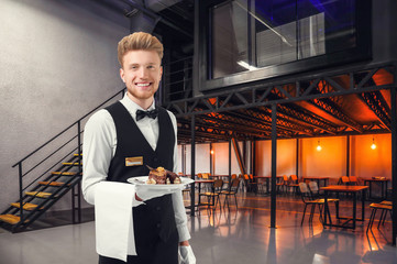 Handsome waiter with menu in modern cafe