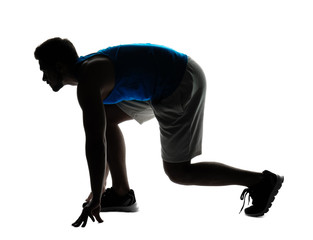 Silhouette of sporty young man in crouch start position on white background