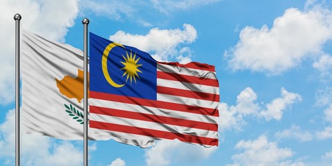 Cyprus and Malaysia flag waving in the wind against white cloudy blue sky together. Diplomacy concept, international relations.