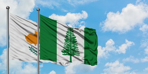 Cyprus and Norfolk Island flag waving in the wind against white cloudy blue sky together. Diplomacy concept, international relations.