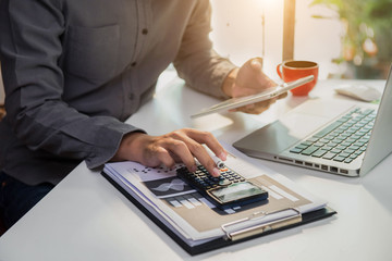 Businessman working on desk office with using a calculator to calculate the numbers, finance...