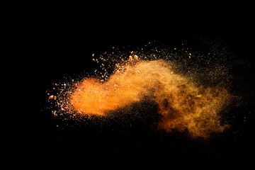 Fototapeta na wymiar Abstract orange powder explosion isolated on black background.