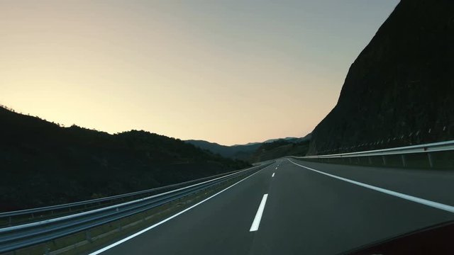 Highway road pov drive against mountains and a sky at the sunrise or sunset