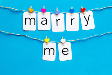 Cute heart icons garland with text marry me on blue background top view