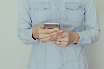 Image of a young woman working on a mobile phone at home on a background of light wall