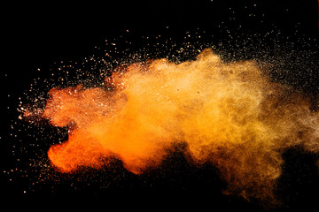 Abstract orange powder explosion isolated on black background.