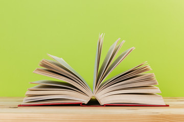 Simple composition of many hardback books, raw of books on wooden table and light green background