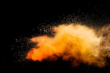 Abstract orange powder explosion isolated on black background.