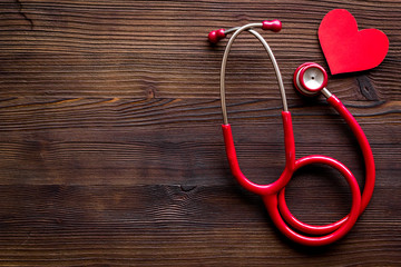 Health care concept. Heart icon and stethoscope on dark wooden background top view space for text