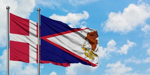 Denmark and American Samoa flag waving in the wind against white cloudy blue sky together....