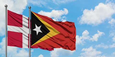 Denmark and East Timor flag waving in the wind against white cloudy blue sky together. Diplomacy concept, international relations.