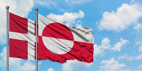 Denmark and Greenland flag waving in the wind against white cloudy blue sky together. Diplomacy concept, international relations.