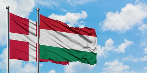 Denmark and Hungary flag waving in the wind against white cloudy blue sky together. Diplomacy concept, international relations.