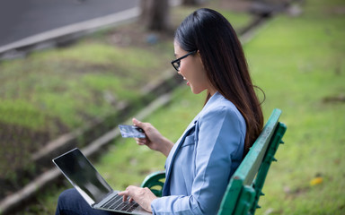 businesswomen using credit card on laptop in park