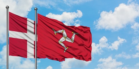 Denmark and Isle Of Man flag waving in the wind against white cloudy blue sky together. Diplomacy concept, international relations.