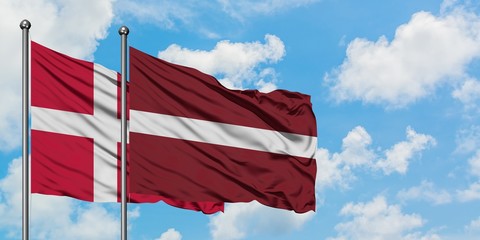 Denmark and Latvia flag waving in the wind against white cloudy blue sky together. Diplomacy concept, international relations.