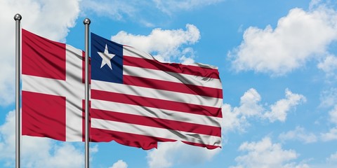 Denmark and Liberia flag waving in the wind against white cloudy blue sky together. Diplomacy concept, international relations.