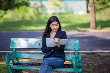 women sitting on bench in park reading paper