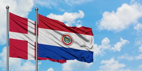Denmark and Paraguay flag waving in the wind against white cloudy blue sky together. Diplomacy concept, international relations.