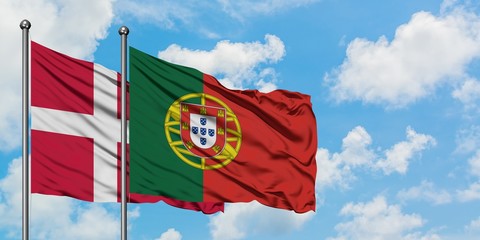Denmark and Portugal flag waving in the wind against white cloudy blue sky together. Diplomacy concept, international relations.