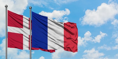 Denmark and Reunion flag waving in the wind against white cloudy blue sky together. Diplomacy concept, international relations.