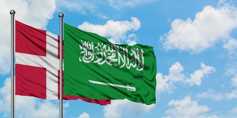 Denmark and Saudi Arabia flag waving in the wind against white cloudy blue sky together. Diplomacy concept, international relations.