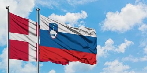 Denmark and Slovenia flag waving in the wind against white cloudy blue sky together. Diplomacy concept, international relations.