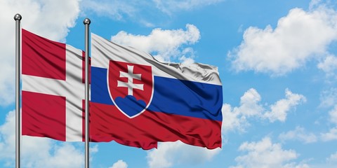 Denmark and Slovakia flag waving in the wind against white cloudy blue sky together. Diplomacy concept, international relations.