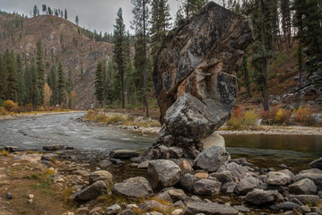 Landscape image of a mountain stream with large rock formation in the foreground.