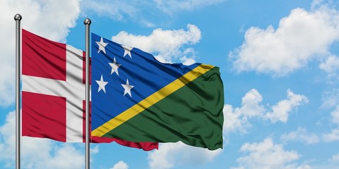 Denmark and Solomon Islands flag waving in the wind against white cloudy blue sky together. Diplomacy concept, international relations.