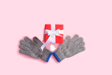 Red gift box, gloves and spruce figurine white on pink background