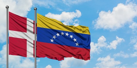 Denmark and Venezuela flag waving in the wind against white cloudy blue sky together. Diplomacy concept, international relations.