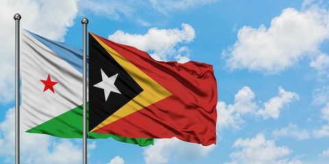 Djibouti and East Timor flag waving in the wind against white cloudy blue sky together. Diplomacy concept, international relations.