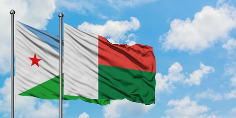 Djibouti and Madagascar flag waving in the wind against white cloudy blue sky together. Diplomacy concept, international relations.