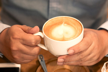 Working man holds a cup of coffee and he is drinking coffee in the cafe.Concept food and drink.