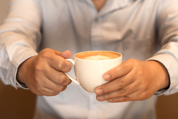 Working man holds a cup of coffee and he is drinking coffee in the cafe.Concept food and drink.