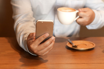 Working man using a mobile phone, with a cup of coffee in the cafe.Business and technology concept.