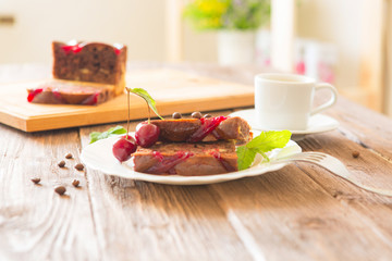 Delicious chocolate cake on plate and cutting board on brown rustic table background