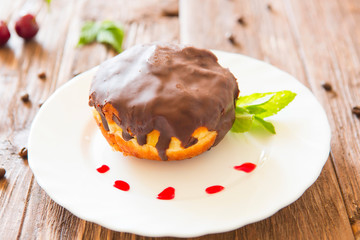 Chocolate donut or bun with on plate on table