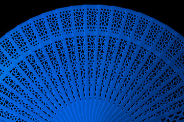 Blue fan with openwork pattern isolated on black background close-up