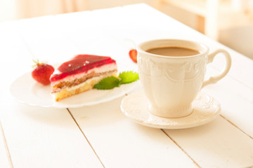 Cup of coffee with strawberry cake on a white wooden table