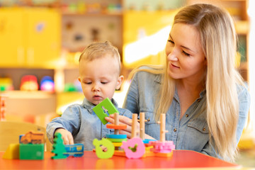 young teacher studying with baby toddler in kindergarten