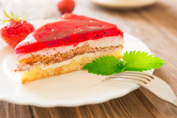 Strawberry cake with leaf of mint on plate on wooden table background