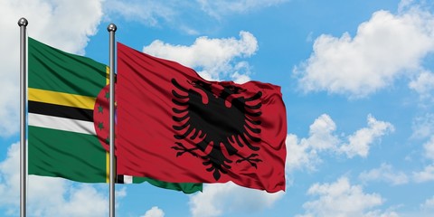 Dominica and Albania flag waving in the wind against white cloudy blue sky together. Diplomacy concept, international relations.