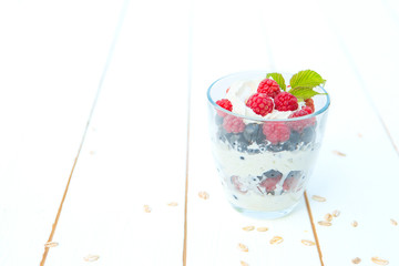 layered dessert with raspberry cream cheese in glass on white wooden table