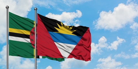 Dominica and Antigua and Barbuda flag waving in the wind against white cloudy blue sky together. Diplomacy concept, international relations.