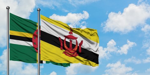 Dominica and Brunei flag waving in the wind against white cloudy blue sky together. Diplomacy concept, international relations.