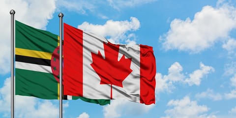 Dominica and Canada flag waving in the wind against white cloudy blue sky together. Diplomacy concept, international relations.