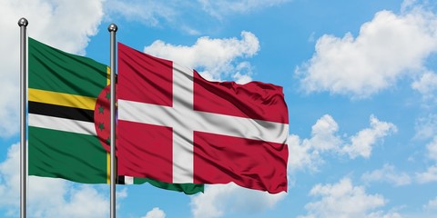 Dominica and Denmark flag waving in the wind against white cloudy blue sky together. Diplomacy concept, international relations.