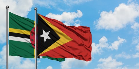 Dominica and East Timor flag waving in the wind against white cloudy blue sky together. Diplomacy concept, international relations.